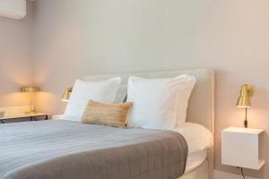 1 dormitorio con 1 cama con almohadas blancas y 2 lámparas en Hello Zeeland - Summum Suites, en Domburg