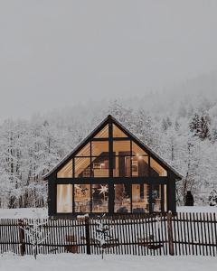 a large glass house in the snow with a fence at Cabana Sapte in Breaza