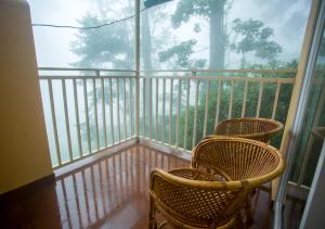 two wicker chairs sitting on a balcony with a window at Areva Inn Munnar by VOYE HOMES in Munnar