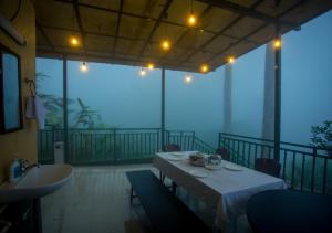 a room with a table on a balcony at Areva Inn Munnar by VOYE HOMES in Munnar
