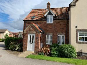 a brick house with a white door on a street at Anchor Down at The Bay, sleeps 4-6 in 2 bedrooms, dogs welcome too in Filey