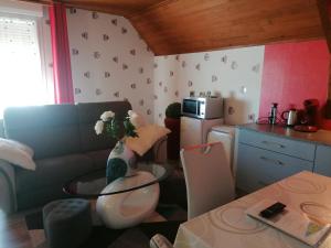 a kitchen with a couch and a table with a vase of flowers at Chambres du Jardin Fleuri in Saint-Aubin-lès-Elbeuf