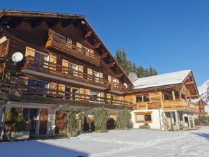 a large wooden building with snow on the ground at Hôtel du Lac des Confins in La Clusaz +3 photos