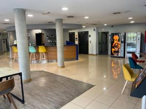 a lobby with columns and a bar with colorful chairs at Holiday Inn Express San Sebastian de los Reyes, an IHG Hotel in San Sebastián de los Reyes