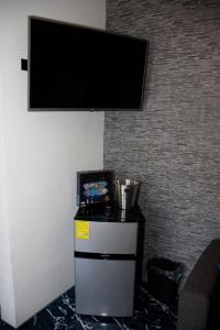 uma televisão de ecrã plano pendurada numa parede com um frigorífico em Hotel Samoa del Sur em Golfito