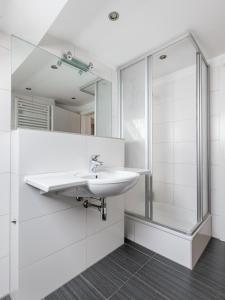 a white bathroom with a sink and a shower at limehome Berlin Kopenhagener Straße in Berlin