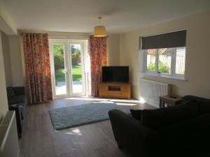 a living room with a flat screen tv and a living room with a couch at Sancia in Hunstanton