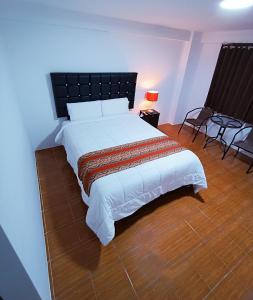 a bedroom with a large white bed with a black headboard at Hostal Cusco de mis Sueños in Cusco