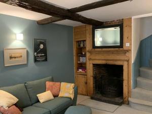 a living room with a couch and a fireplace with a television at Smuggler's Cottage in Deal
