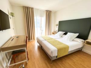 a hotel room with a large bed and a desk at FAY Victoria Beach in Rincón de la Victoria