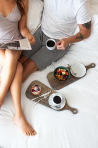 un homme et une femme assis sur un lit avec de la nourriture et des boissons dans l'établissement SANA Malhoa Hotel, à Lisbonne