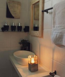 a bathroom with a sink and a candle on a counter at ALLURING SELF CATERING 2 BEDROOM VILLA at BOKMAKIERIE VILLAS in Windhoek