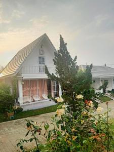 une maison blanche avec un arbre en face dans l'établissement ภูฝ้ายวิลล่า Phufai villa, à Chiang Khan