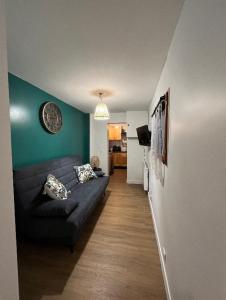 a living room with a black couch and a green wall at Adorable F1, au bord du lac d’élancourt village in Élancourt