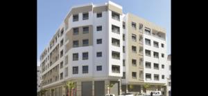 um edifício alto e branco com carros estacionados em frente em Bel appart+2 ROOM+WIFI+GARE CASA VOYAGEUR+TRAM em Casablanca
