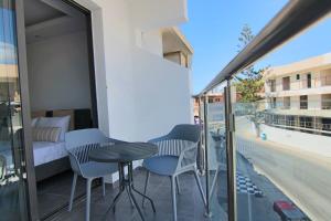 - un balcon avec une table, des chaises et un lit dans l'établissement Phaedrus Living: Seaside Luxury Flat Athina 117, à Paphos