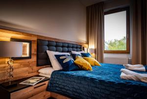 Un dormitorio con una cama azul con almohadas y una ventana en APARTHOTEL Wałcz, en Wałcz
