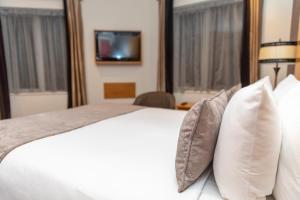 a bedroom with a white bed with pillows and a tv at Tara Lodge in Belfast