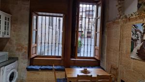 a dining room with a table and two windows at LAS CATEDRALES De SALAMANCA in Salamanca