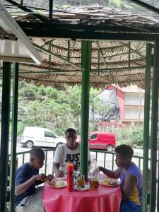 Eine Gruppe von drei Männern, die an einem Tisch sitzen und Essen essen. in der Unterkunft pam de terra 