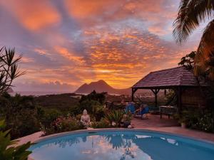 une piscine du complexe avec un coucher de soleil en arrière-plan dans l'établissement TI coin de paradis Frangipanier, au Diamant