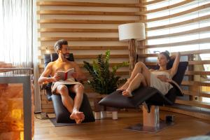 a man and a woman sitting in chairs reading at Hotel Nordik in Andalo