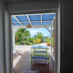 an open door to a patio with a table on a deck at Ti coin de paradis Ylang Ylang in Le Diamant