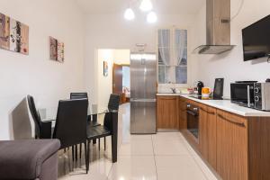 a kitchen with a table and a stainless steel refrigerator at Superbly Located Cosy 2-Bedroom Apartment Valletta in Valletta