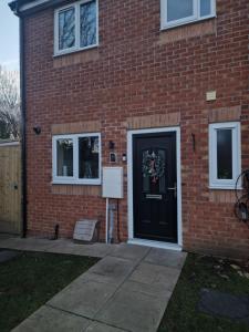 a brick house with a black door with a wreath on it at Cheerful 3 Bedroom Town House With Hot Tub in Blackpool