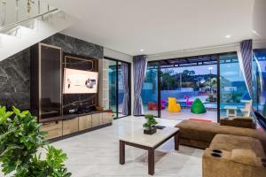 ein Wohnzimmer mit einem großen TV und einem Sofa in der Unterkunft Ban Kiang Rak pool villa Hua Hin บ้านเคียงรักพูลวิลล่าหัวหิน in Hua Hin