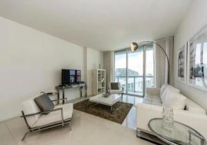 een woonkamer met een witte bank en een tafel bij Luxurious 1BR Condo At Icon Brickell in Miami