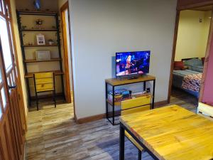 een woonkamer met een tafel en een tv en een slaapkamer bij Cabañas Ventalia in El Calafate