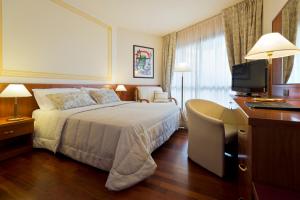 a hotel room with a bed and a desk with a television at Savoy Beach Hotel & Thermal Spa in Bibione