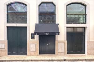 里斯本Ando Living - Douradores House的一栋带有三扇黑色车库门的建筑