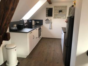 a kitchen with white cabinets and a black refrigerator at Apartment Maria in Kürten