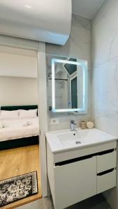 ein Bad mit einem Waschbecken, einem Spiegel und einem Bett in der Unterkunft Kristi Apartments 01 in Tirana