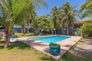 a swimming pool in a yard with palm trees at Casa Dunas - Espaço e Conforto em PDD by Carpediem in Aquiraz