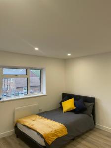 a bedroom with a bed with a yellow blanket on it at London Studios in BR54LT in Saint Mary Cray