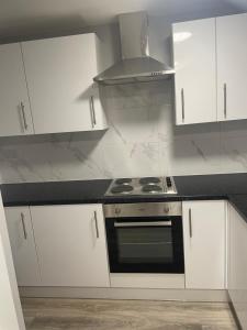 a white kitchen with a stove and white cabinets at London Studios in BR54LT in Saint Mary Cray