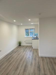 an empty living room with white walls and wood floors at London Studios in BR54LT in Saint Mary Cray