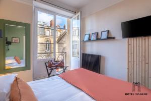 a bedroom with a bed and a large window at Hôtel Madame in Bordeaux