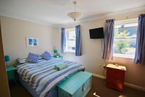 a bedroom with a bed with a blue cabinet and windows at Gerald's Place in Deal