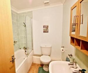 a bathroom with a toilet and a tub and a sink at Gerald's Place in Deal