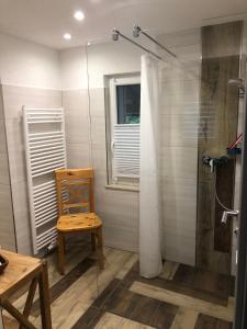 a bathroom with a shower and a wooden chair at Casa „Ella“ in Friedrichroda