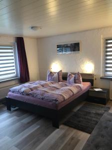 duże łóżko w sypialni z dwoma oknami w obiekcie Casa „Ella“ w mieście Friedrichroda