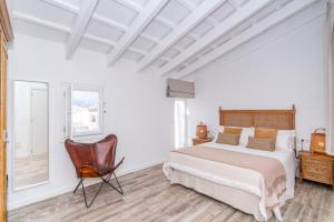 a white bedroom with a bed and a chair at Encant de Alaior Boutique Hotel in Alaior