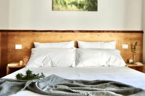 a bedroom with a white bed with a wooden headboard at Case Verdi in Bardonecchia