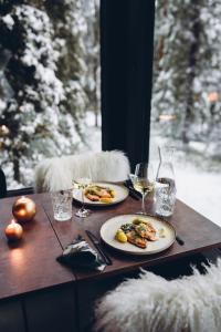 a table with two plates of food and glasses of wine at Magical Pond Nature Igloos in Ruka