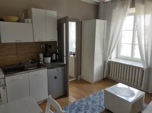 ワルシャワにあるDwupokojowe mieszkanie w Centrumの白いキャビネット、シンク、窓付きのキッチン