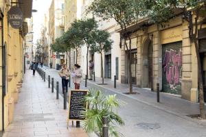 a woman standing on a street with a sign on a sidewalk at ApartEasy - Central Gracia Apartments in Barcelona